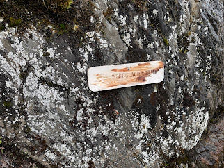 West Glacier carved wooden trail sign on lichen-covered rock